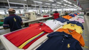 Custom polo t-shirts stacked in a warehouse, ready for bulk purchase, with a variety of colors and sizes.